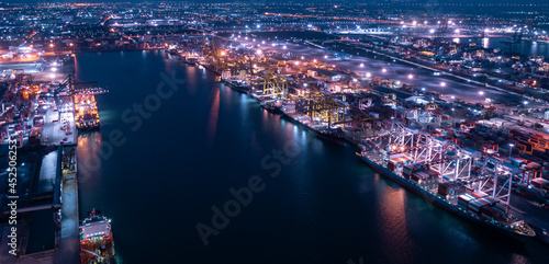 Containers ship and ports logistic freight load unloading by crane industry and business service shipping import export goods transportation of international at night scene aerial view © SHUTTER DIN