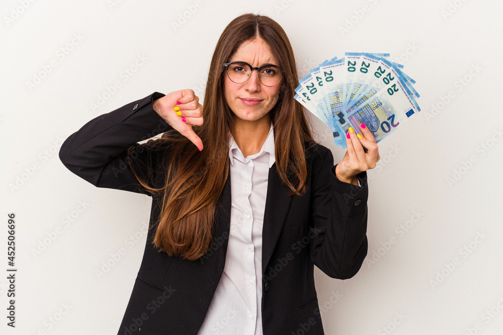 Young caucasian business woman holding banknotes isolated on white background showing a dislike gesture, thumbs down. Disagreement concept. Young caucasian business woman holding banknotes isolated on white background showing a dislike gesture, thumbs down. Disagreement concept.