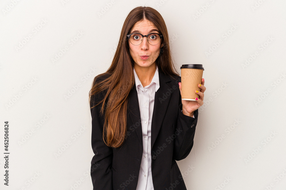 Young caucasian business woman holding a takeaway coffee isolated on white background shrugs shoulders and open eyes confused. Young caucasian business woman holding a takeaway coffee isolated on white background shrugs shoulders and open eyes confused.