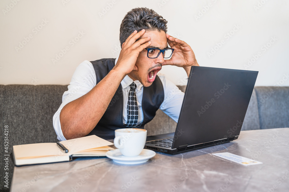 Hispanic businessman impressed with what appears on his laptop Hispanic businessman impressed with what appears on his laptop