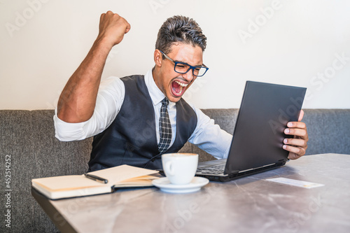 Hispanic businessman elated with what appears on his laptop