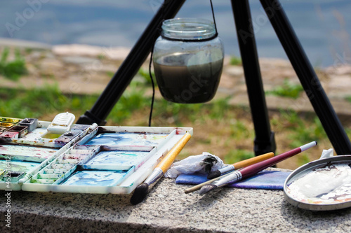 Brushes and paints, easel. Plein air, painting with watercolors. Artist painting on the street
