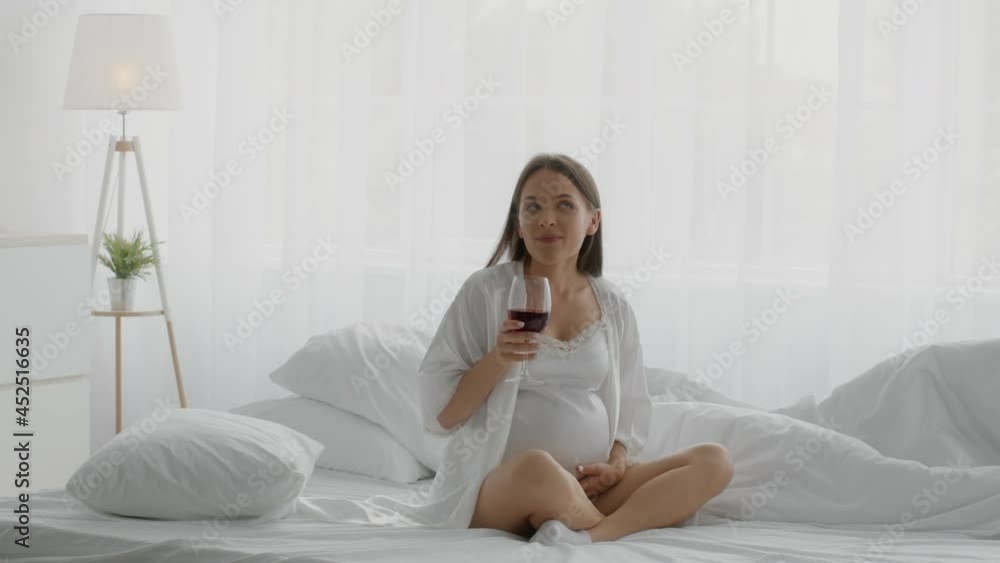 Pregnancy And Alcohol. Young Pregnant Lady Drinking Wine While Relaxing In Bed Pregnancy And Alcohol. Young Pregnant Lady Drinking Wine While Relaxing In Bed