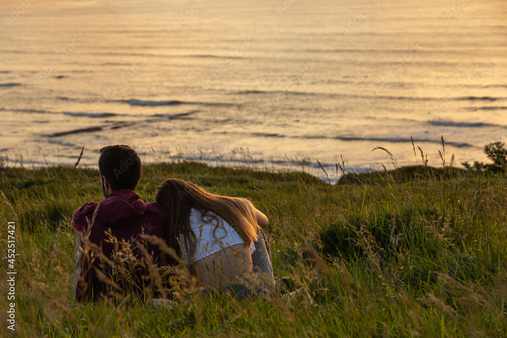 sweet young couple enjoying sunset together in front of the sea