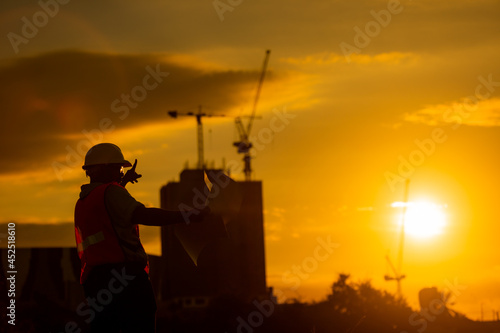 silhouette of engineer and construction site background at sunset