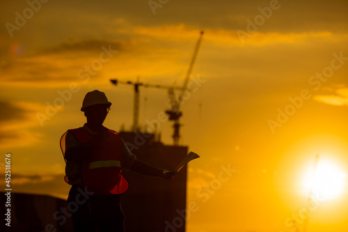 silhouette of engineer and construction site background at sunset