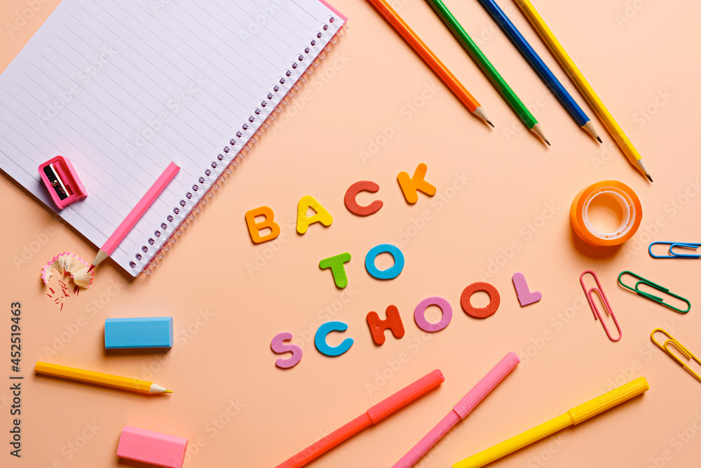 Back to school note on a peach colored background with a notebook and colorful pencils. September inspired school arrangement. Getting ready for classes. Backpack equipment, flat lay. Back to school note on a peach colored background with a notebook and colorful pencils. September inspired school arrangement. Getting ready for classes. Backpack equipment, flat lay.
