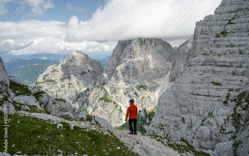 Active male hiker enjoying the view. Hiking man adventure travel explorer hiker on mountain summit looking at landscape view. Adventure, Explore and Lifestyle Concept Composite. Alpi Giulie