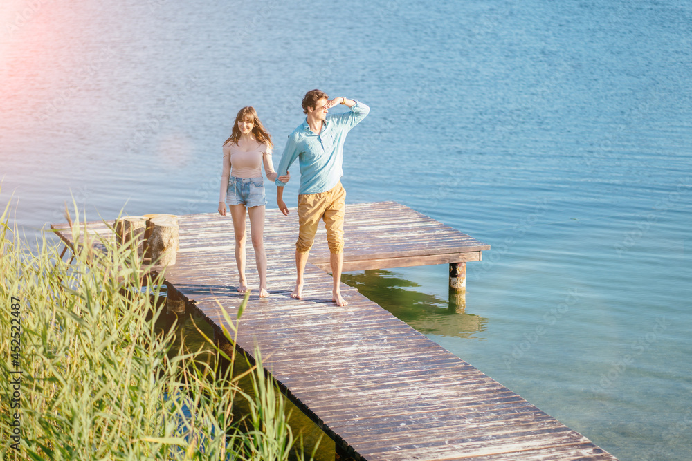 Fototapeta premium Lovely couple on wooden bridge at summer sunny day.