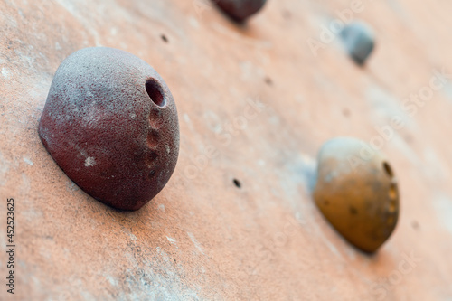 Close-up photo of climbing holds on worn wall outside. Artificial rock climbing wall at park.