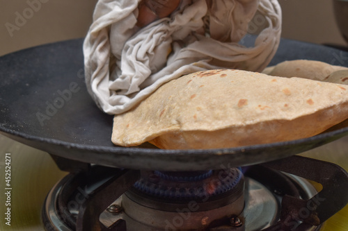 Indian soft phulka Chapati (roti) on non stick tawa making with hands photo