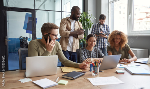 Working on project together. Group of multiracial coworkers communicating, talking, sharing fresh ideas while working in the modern coworking space