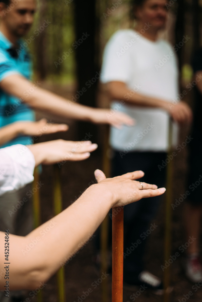 Vertical photo of people standing in a circle and holding a stick. Team building exercise. High quality photo