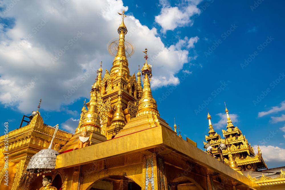 Fototapeta premium The castle mondop square hall with a pyramidal roof and the golden pagoda in the Burmese temple