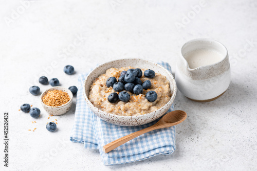 Vegan oatmeal porridge with blueberries and flax seeds on natural grey background. Healthy eating, dieting, fitness food lifestyle concept