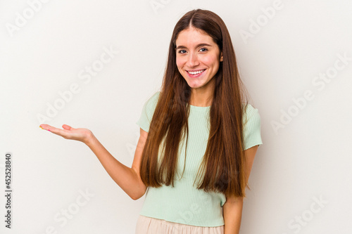 Young caucasian woman isolated on white background showing a copy space on a palm and holding another hand on waist.