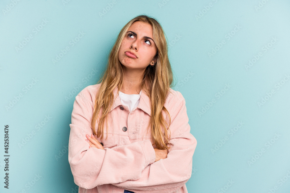 Young caucasian blonde woman isolated on blue background tired of a repetitive task. Young caucasian blonde woman isolated on blue background tired of a repetitive task.