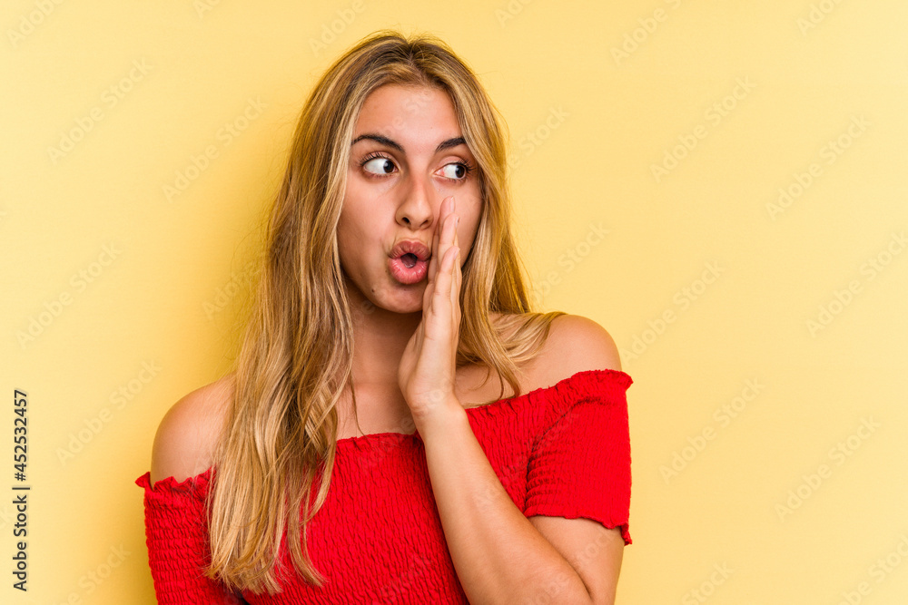 Young caucasian blonde woman isolated on yellow background is saying a secret hot braking news and looking aside Young caucasian blonde woman isolated on yellow background is saying a secret hot braking news and looking aside