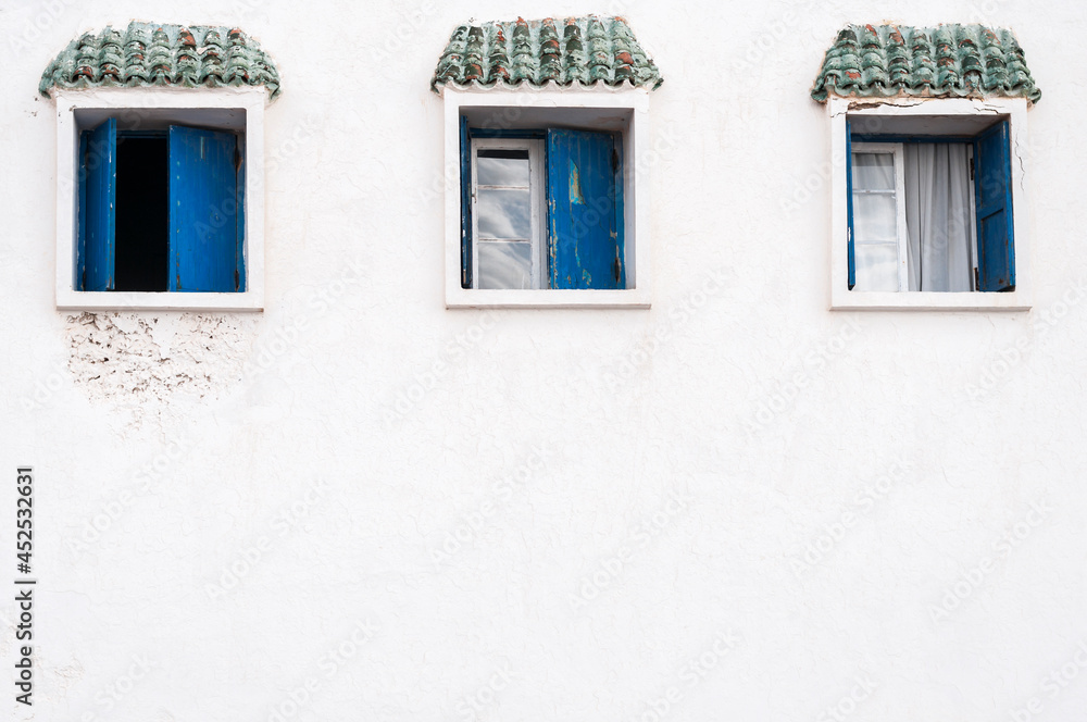 White house facade with windows / White house facade with three blue windows.