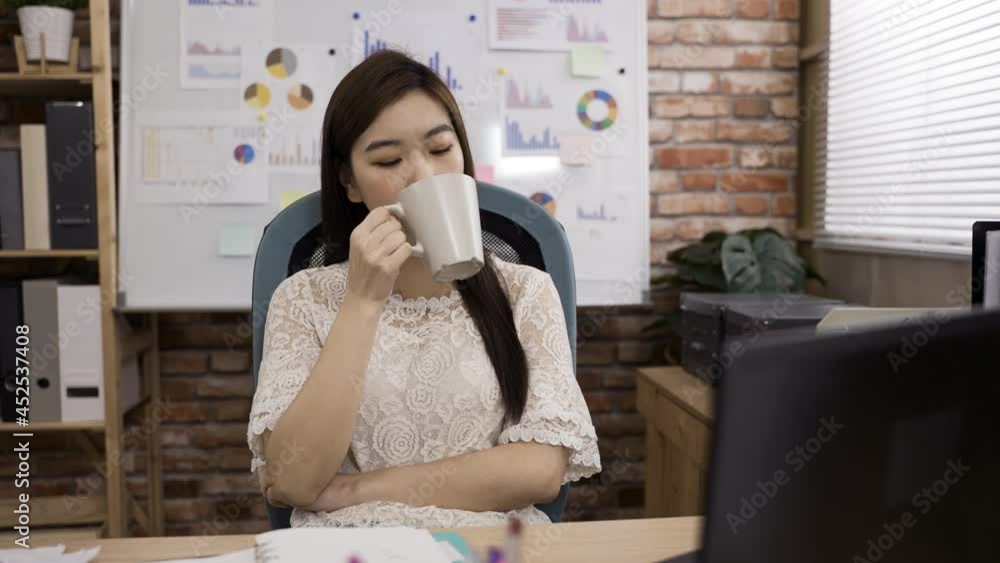 portrait of a beautiful asian female entrepreneur is gazing into the distance in contemplation while having a tea break at desk in the office. portrait of a beautiful asian female entrepreneur is gazing into the distance in contemplation while having a tea break at desk in the office.