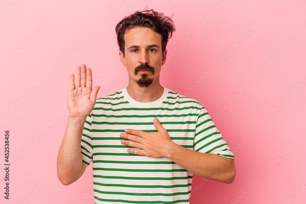 Young caucasian man isolated on pink background taking an oath, putting hand on chest. Young caucasian man isolated on pink background taking an oath, putting hand on chest.