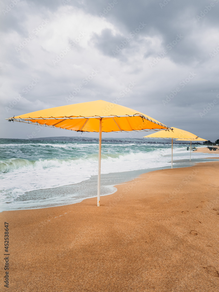 Yellow beach umbrellas on the sand. Storm.