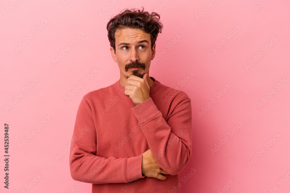 Young caucasian man isolated on pink background looking sideways with doubtful and skeptical expression. Young caucasian man isolated on pink background looking sideways with doubtful and skeptical expression.