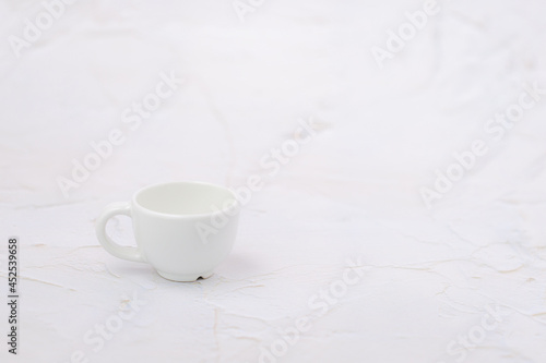 White cup of coffee on the white rough background with copy space for drinks and beverage concept