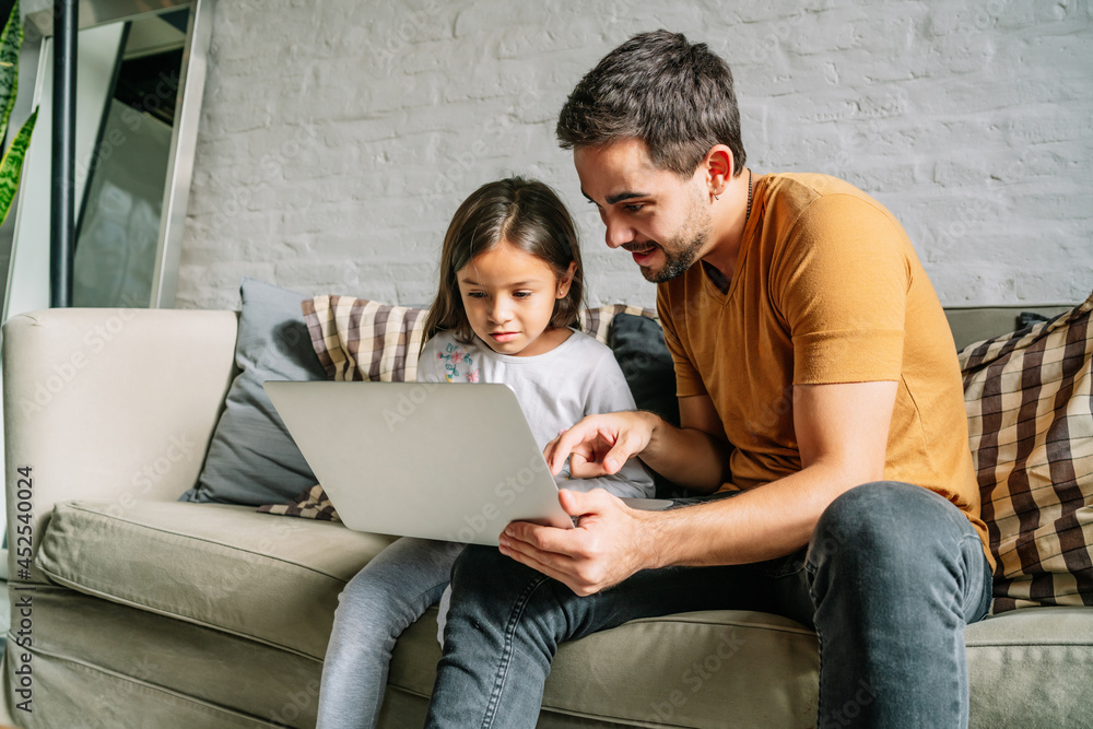 Little girl and her father using a laptop together at home. Little girl and her father using a laptop together at home.