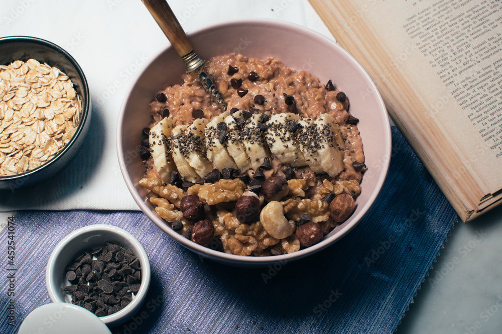 Bowl of oatmeal porridge with banana and nuts. Top view. Healthy vegan breakfast