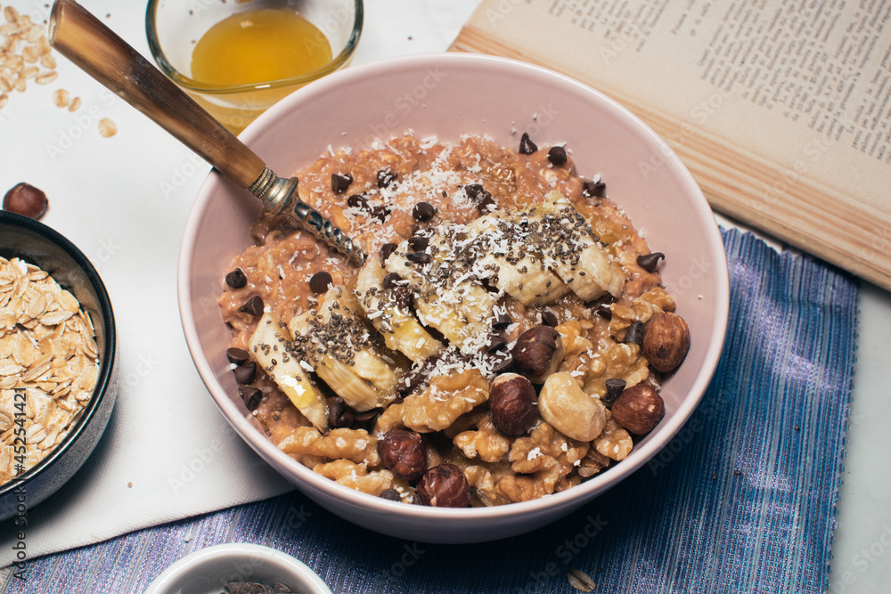 Bowl of oatmeal porridge with banana and nuts. Top view. Healthy vegan breakfast