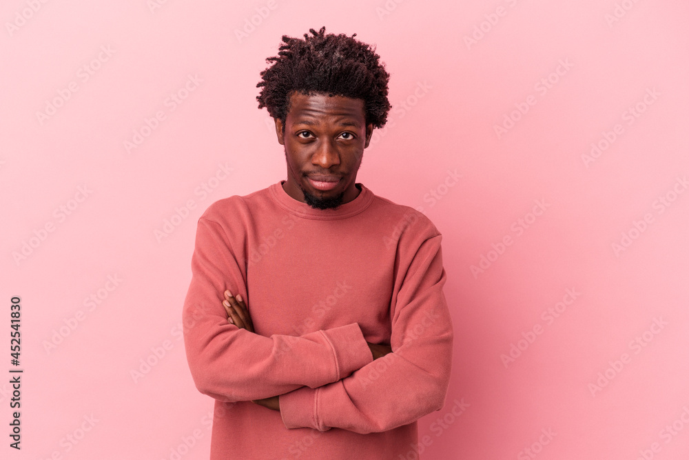 Young african american man isolated on pink background suspicious, uncertain, examining you. Young african american man isolated on pink background suspicious, uncertain, examining you.