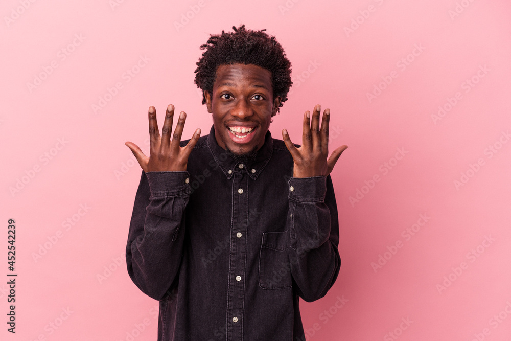 Young african american man isolated on pink background showing number ten with hands. Young african american man isolated on pink background showing number ten with hands.