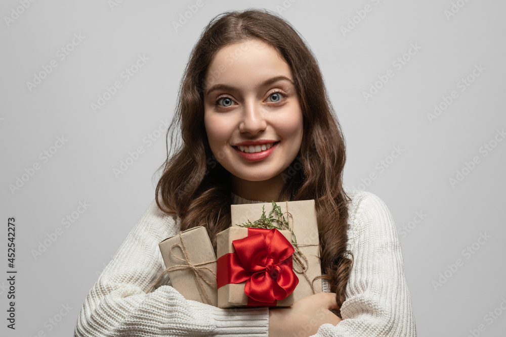 A young girl with long hair and a gift in her hands, smiling and looking straight at the camera A young girl with long hair and a gift in her hands, smiling and looking straight at the camera