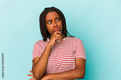 Young african american woman isolated on blue background relaxed thinking about something looking at a copy space.