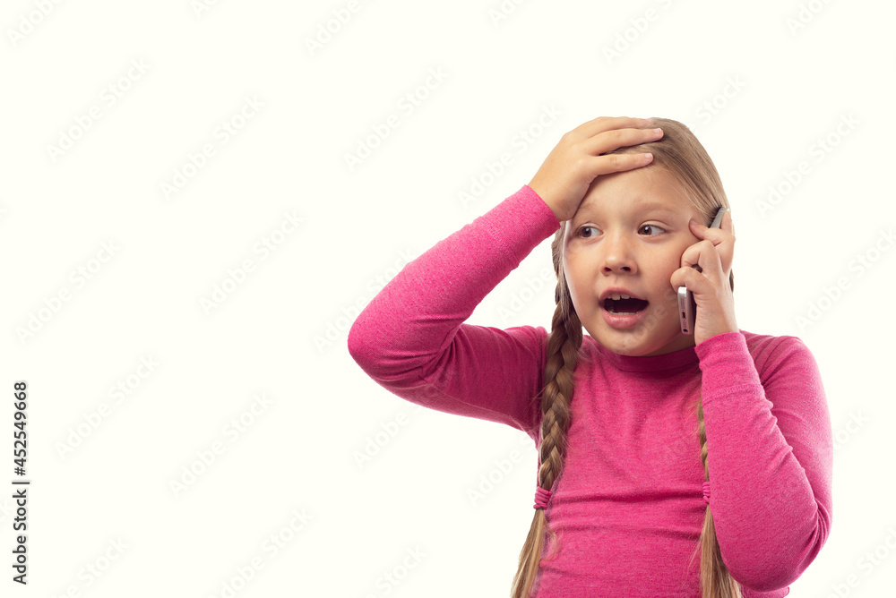 The girl is talking on the phone. Beautiful excited surprised little girl having conversation with friends mobile phone isolated on white background. Surprised emotions human face expressions. The girl is talking on the phone. Beautiful excited surprised little girl having conversation with friends mobile phone isolated on white background. Surprised emotions human face expressions.