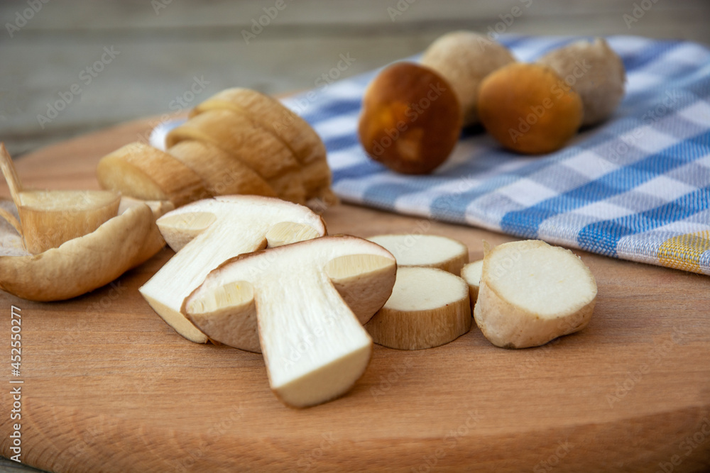 Sliced porcini mushrooms on a cutting board. Edible mushrooms on a checkered towel. Sliced porcini mushrooms on a cutting board. Edible mushrooms on a checkered towel.