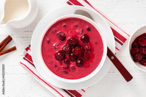 Sour cherry soup in a white bowl on a white background. Top view. Hungarian cold cherry soup with cream or sour cream, sugar and cinnamon. Sweet summer soup.