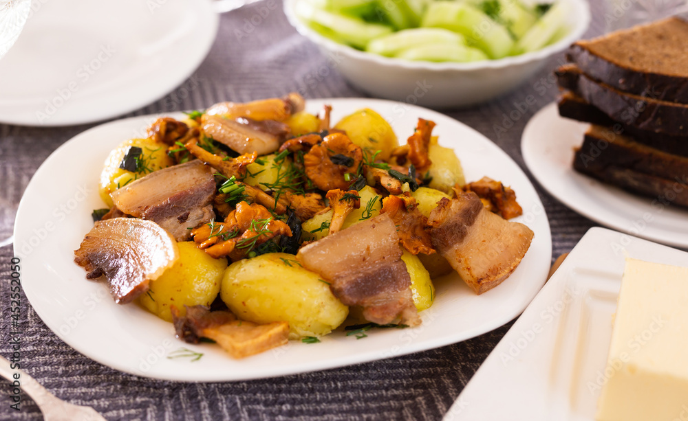 traditional rustic dish. fried potatoes with chanterelle mushrooms and pork brisket with herbs