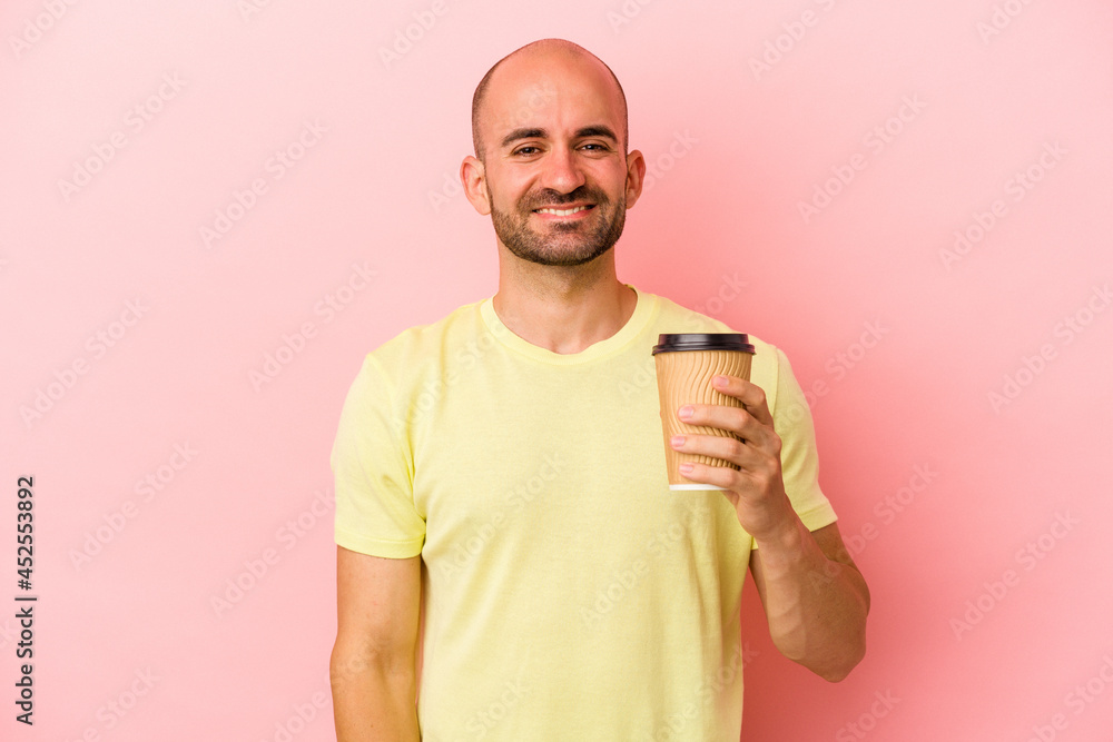 Young caucasian bald man holding a take away coffee isolated on pink background happy, smiling and cheerful. Young caucasian bald man holding a take away coffee isolated on pink background happy, smiling and cheerful.