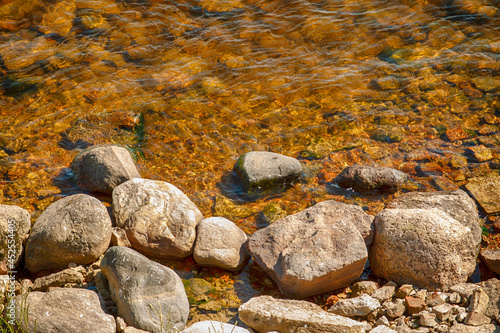 Small stones on the bank of the river with clear water.