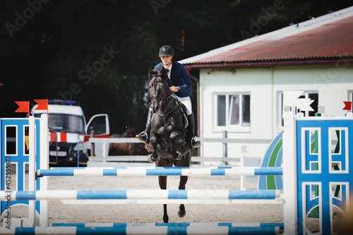 black stallion horse and handsome man rider jumping obstacle
