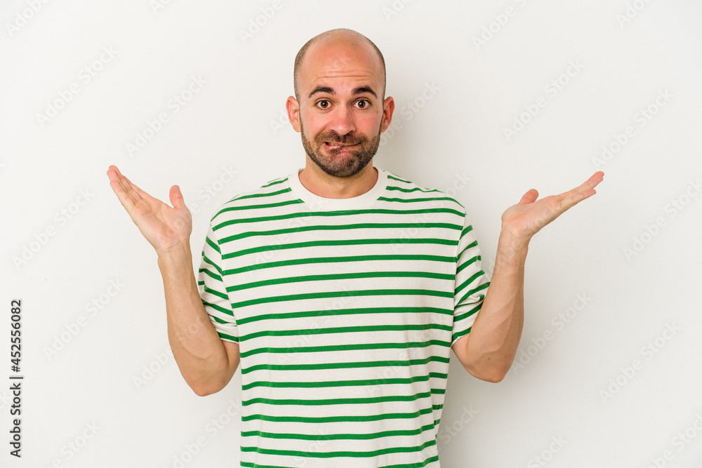 Young bald man isolated on white background confused and doubtful shrugging shoulders to hold a copy space. Young bald man isolated on white background confused and doubtful shrugging shoulders to hold a copy space.
