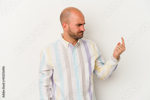 Young bald man isolated on white background pointing with finger at you as if inviting come closer. © Asier
