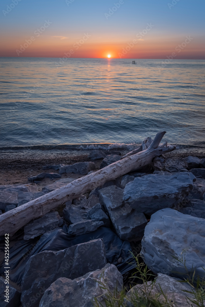Dead tree and boulders along lake Michigan during sunset Dead tree and boulders along lake Michigan during sunset