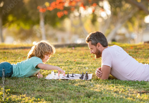 strategic and tactic. tutorship. dad and kid play logic game. father and son playing chess