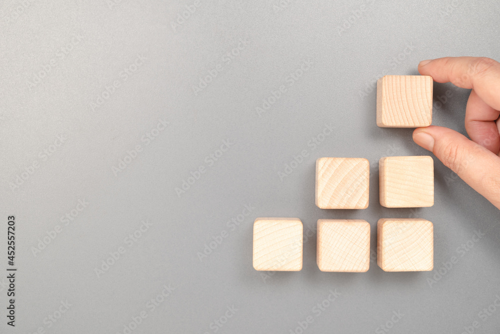 Hand put the last piece on the top of step stairs wood cubes, abstract wood cubes of success, process, teamwork, and goal in business Hand put the last piece on the top of step stairs wood cubes, abstract wood cubes of success, process, teamwork, and goal in business