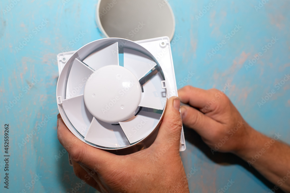 Fototapeta premium Man is installing the wall bathroom fan vent. Restoration process. Wires in hands. Maintenance repair works renovation in the flat.