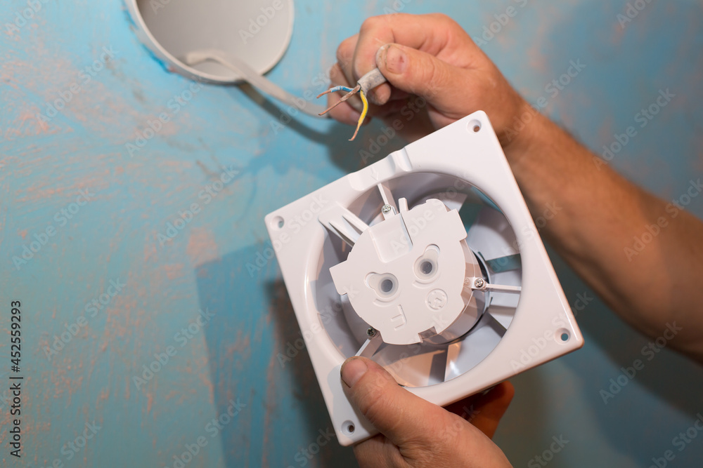 Man is installing the wall bathroom fan vent. Restoration process