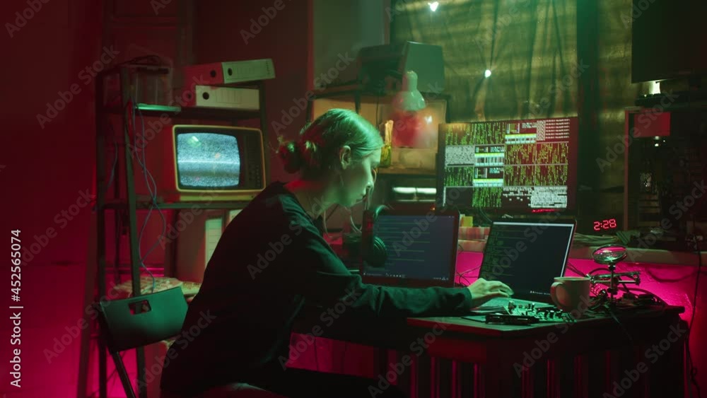 Young hacker typing on keyboard at night, breaking password, using laptop and drinking coffee at night. Woman developing program in dark room. Programmer infecting system with cyber virus Young hacker typing on keyboard at night, breaking password, using laptop and drinking coffee at night. Woman developing program in dark room. Programmer infecting system with cyber virus